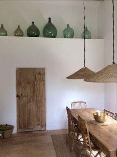 a wooden table sitting under hanging lights next to a wall with vases on it