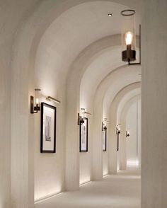 the hallway is lined with arches and framed pictures on the wall, along with two lamps