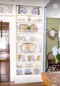 the shelves are filled with dishes and vases on top of each other in front of a wooden door