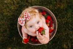 a baby girl eating strawberries in a bowl