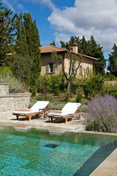 two chaise lounge chairs next to a swimming pool