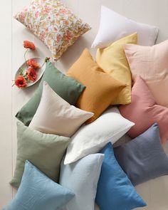 many pillows are laying on the floor next to each other and one has a plate with flowers in it