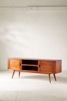 a wooden entertainment center in an empty room with white walls and concrete flooring on the side