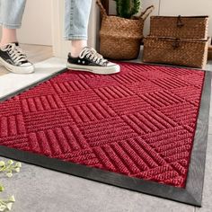 a woman standing on the floor in front of a red rug with black trimming