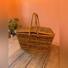 a brown wicker basket sitting on top of a wooden table next to a potted plant