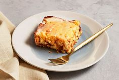 a piece of cake sitting on top of a white plate next to a gold fork