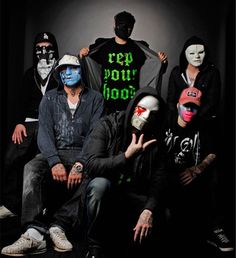 group of people with painted faces sitting in front of a black background and wearing masks