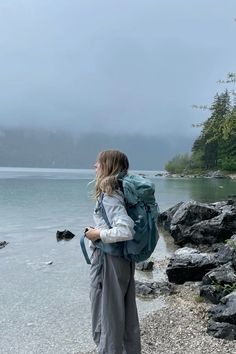 a woman with a backpack is standing by the water