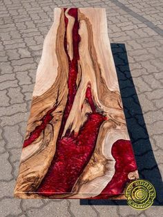 a piece of wood with red paint on it sitting on the ground next to a black mat