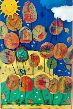 an art project made with colored paper and leaves on a blue background, including the sun