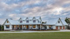 a large white house sitting on top of a lush green field under a cloudy sky