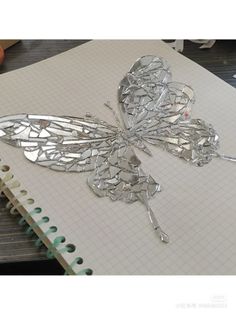 a butterfly made out of broken glass sitting on top of a notebook