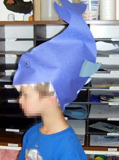 a young boy wearing a blue hat with a fish on it's head in front of shelves