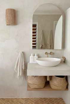 a bathroom with a sink, mirror and two baskets on the counter in front of it