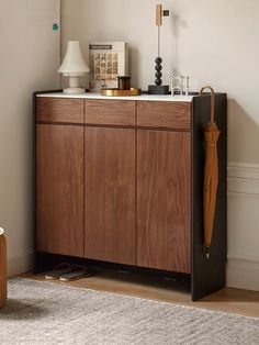 a wooden cabinet with an umbrella and other items on it in a living room area