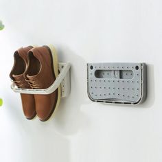 a pair of shoes hanging on a wall next to a shoe rack with two pairs of shoes