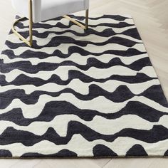 a black and white area rug with wavy lines on the floor in front of a chair