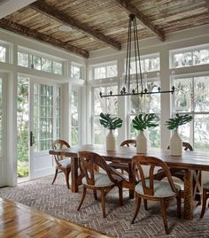 the dining room table is surrounded by chairs and vases with plants in them on either side