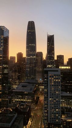 the city skyline is lit up at night, with skyscrapers in the foreground