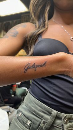 a woman with a tattoo on her arm that reads, god's speed in cursive writing