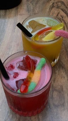 two glasses filled with different colored drinks on top of a wooden table next to each other