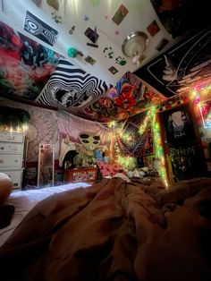 a bedroom decorated with colorful lights and pictures on the ceiling, along with an unmade bed