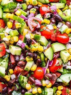 a salad with cucumbers, tomatoes, black beans, corn and cilantro