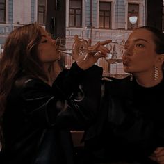 two women are drinking wine out of glasses