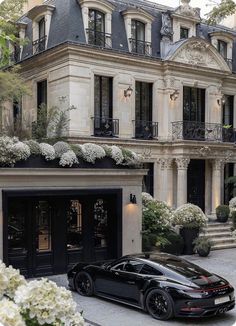 a black sports car is parked in front of a large building with many windows and balconies