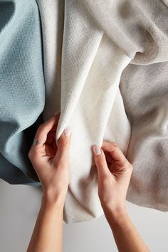 two hands are holding fabric on top of each other