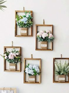 four square wooden frames with flowers hanging on the wall in front of a white wall