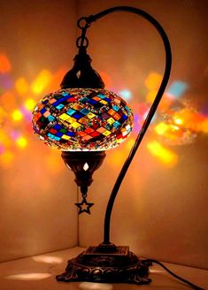 a stained glass lamp on a table in front of a wall with multicolored lights