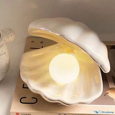 a white vase sitting on top of a table next to an egg shell shaped lamp