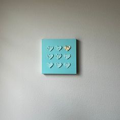 a blue square with hearts cut out of it hanging on the wall next to a bed