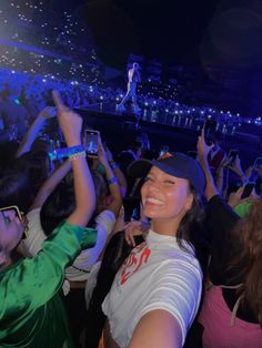 a group of people at a concert with their hands in the air and one person holding up his cell phone