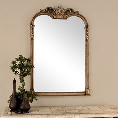 a mirror sitting on top of a table next to vases and a potted plant