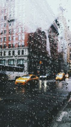 rain drops on the window as cars drive down a city street in front of buildings