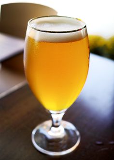 a glass of beer sitting on top of a wooden table