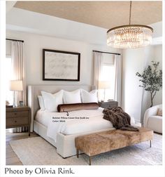 a bed room with a neatly made bed and a chandelier hanging from the ceiling