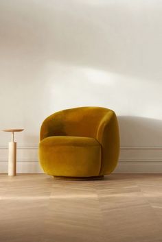 a yellow chair sitting on top of a hard wood floor next to a white wall