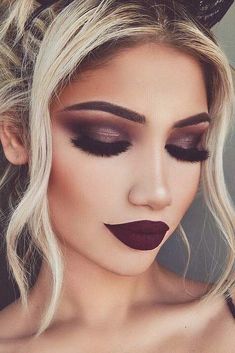 a woman with long blonde hair and black makeup looks like she is wearing dark lipstick