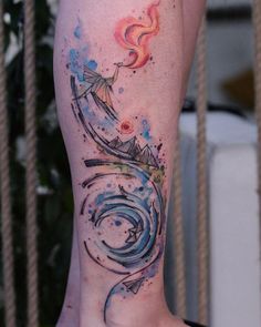 a woman's leg with watercolor tattoos on it and an arrow in the middle