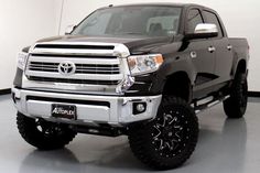 a black and white truck is parked in a room with large tires on the rims