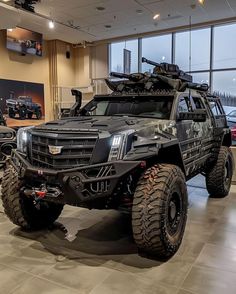 an armored vehicle is on display in a showroom with other vehicles and people looking out the window