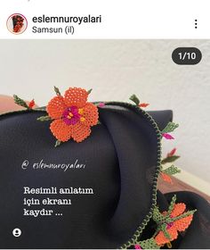 an orange flower is on top of a black bag that has words written in it