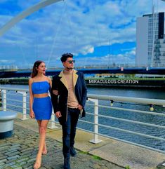 a man and woman walking down a sidewalk next to the water