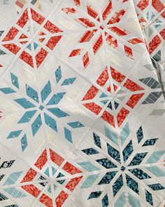 a close up of a quilt with red, white and blue snowflakes on it