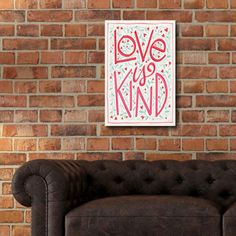 a couch sitting in front of a brick wall with a love is kind sign on it