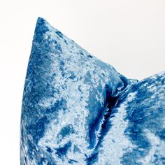 a blue pillow that is sitting on top of a white surface with no one around it