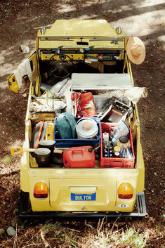 the back end of a yellow van filled with assorted items